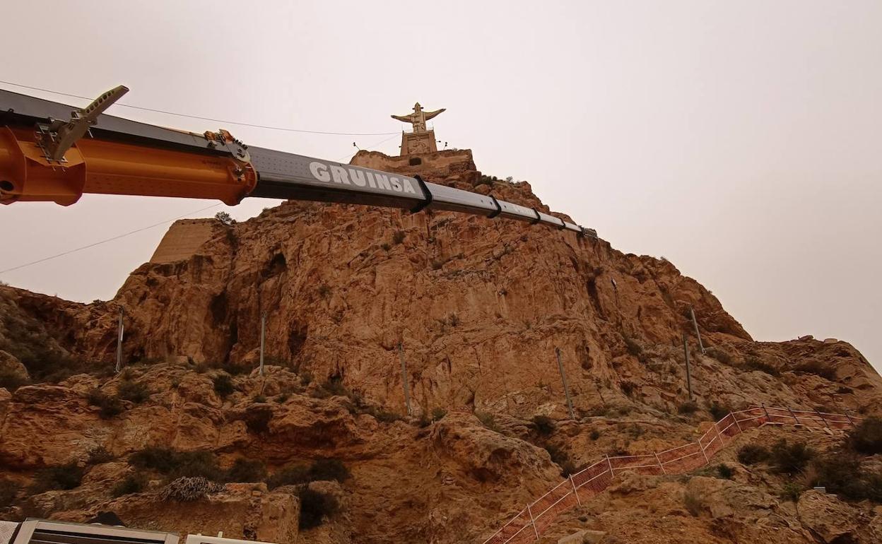 Una grúa monta las barreras en la falda del promontorio del castillo.