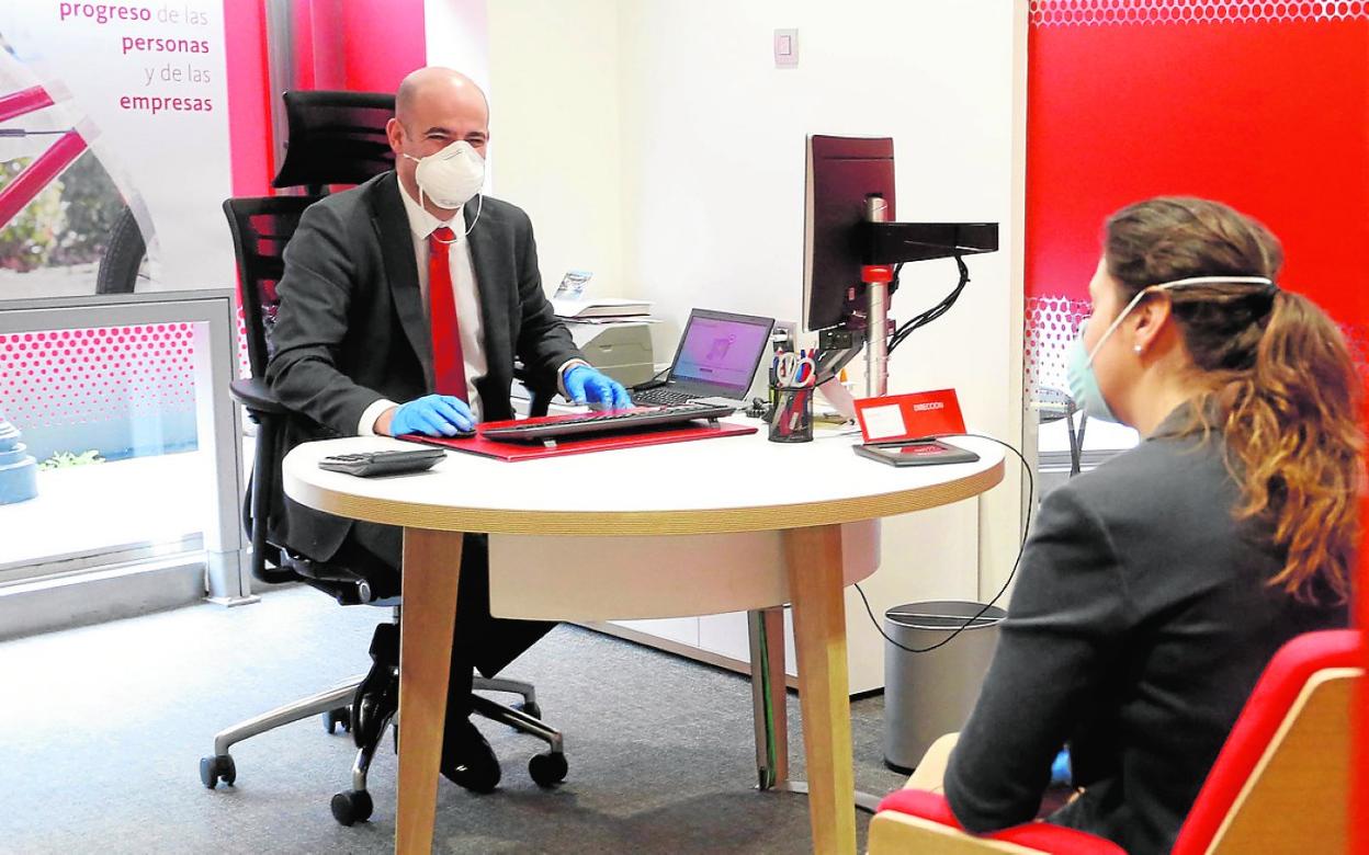 Un director de sucursal atiende a una empresaria para un contrato de 'factoring', en abril de 2020. 