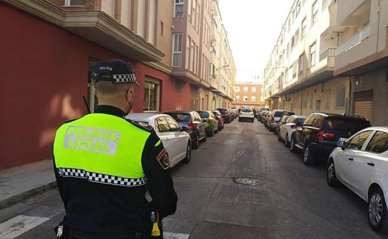 Un agente de la Policía Local vigila la calle Rafael Hervás de Sueca, lugar del crimen.