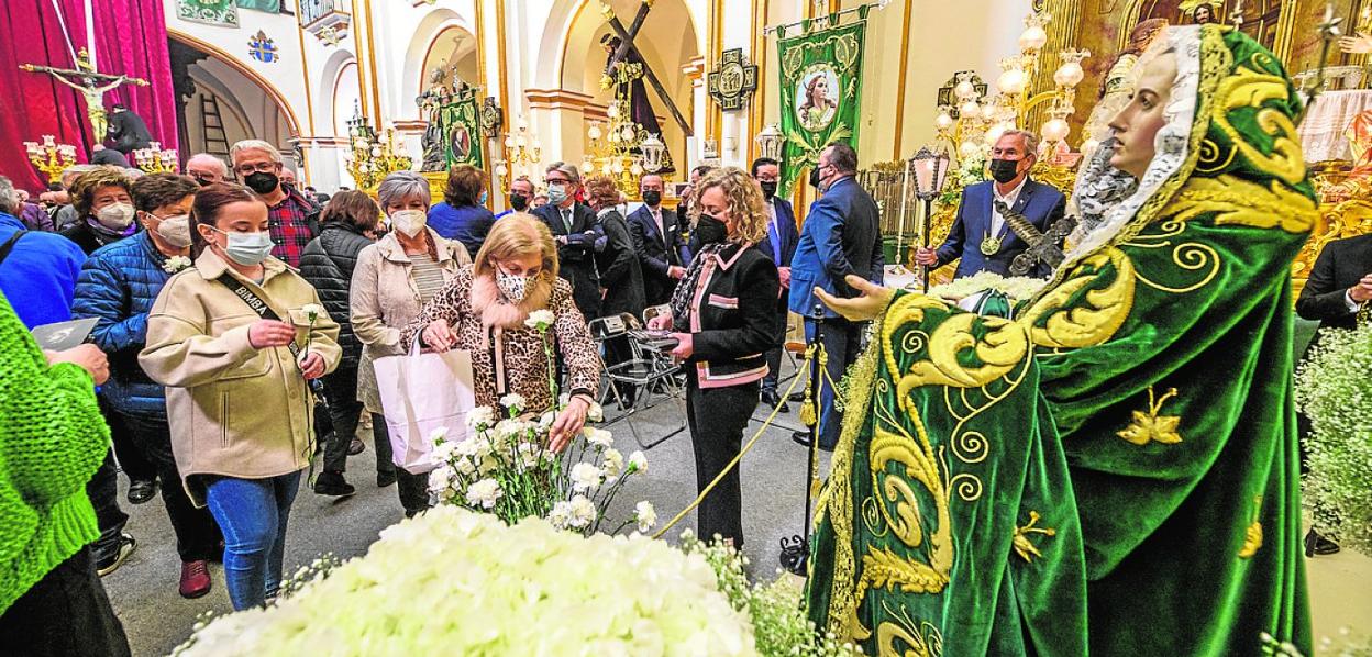Fieles de la Virgen de los Dolores recogen en la iglesia de San Pedro Apóstol un clavel como recuerdo del besamanos, que no se hizo por la Covid; al fondo a la izquierda, el Cristo de la Esperanza. 