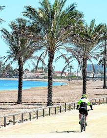Imagen secundaria 2 - Arriba, operarios rehabilitan la arena de una playa de Lo Pagán, este viernes; a la izquierda, un tractor iguala la arena de una playa de Águilas; y, a la derecha, un ciclista pasea junto al Mar Menor, en Playa Paraíso.