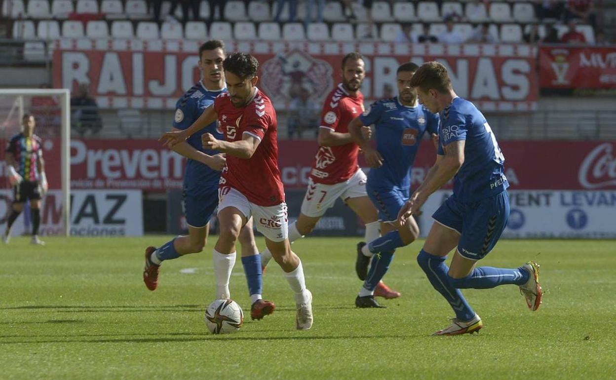 Javi Saura avanza con el balón entre los jugadores del Puertollano.