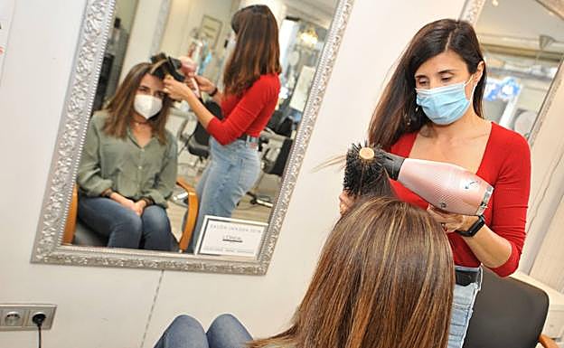 Una empleada y una clienta utilizan sendas mascarillas en la peluquería Alfonso X de Murcia, ayer. 