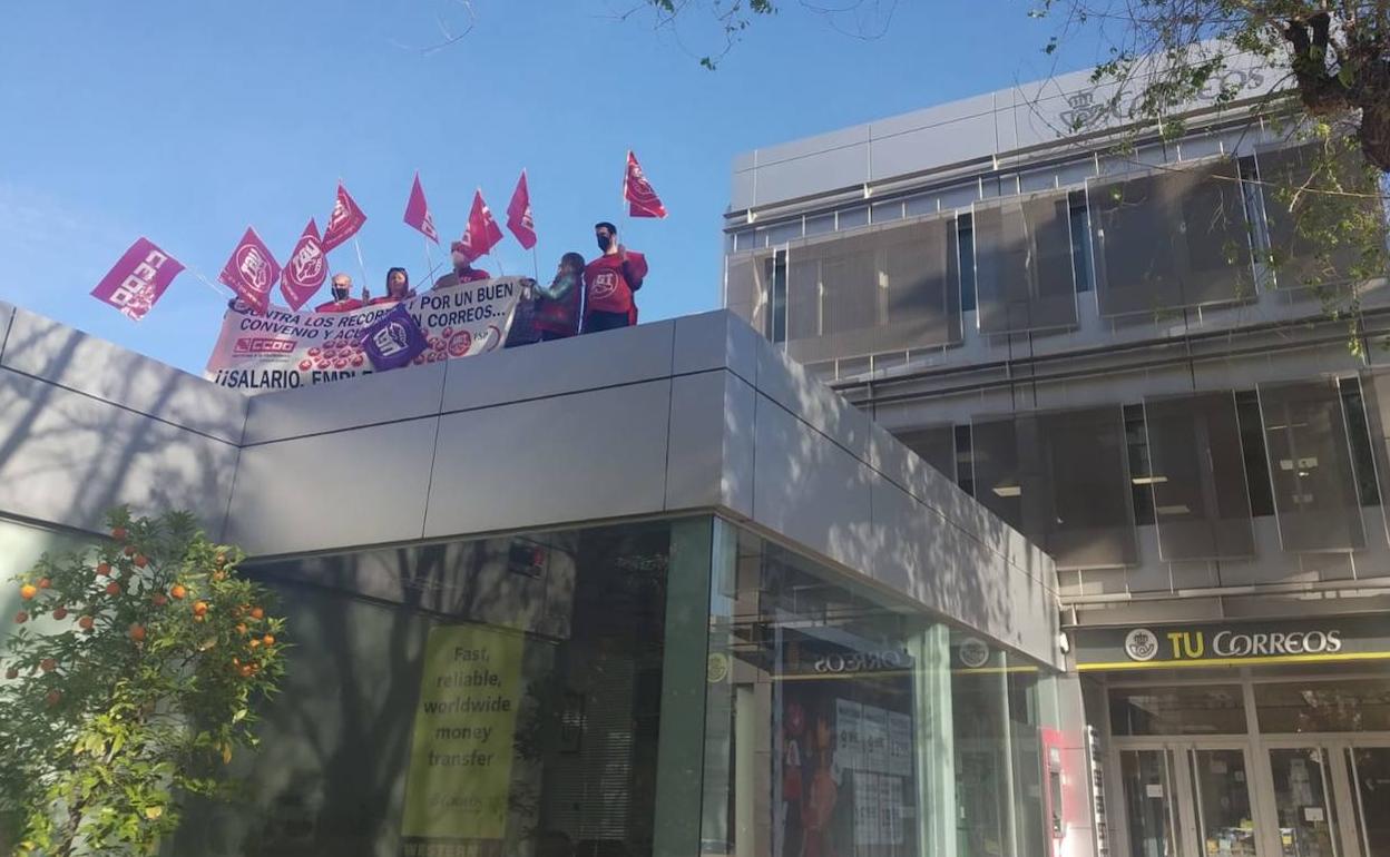 Delegados de CC OO y UGT protestan en la azotea de la sede central de Correos.