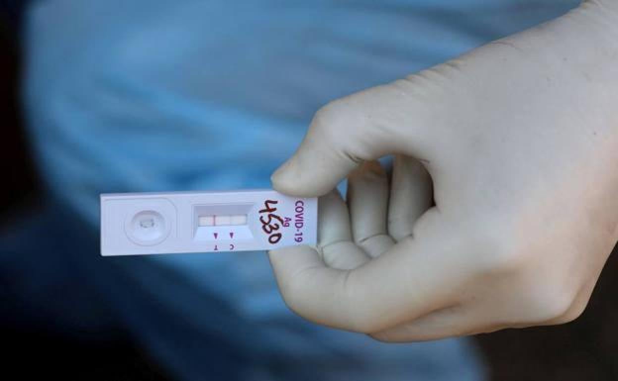Un sanitario sostiene un test de antígenos positivo. 