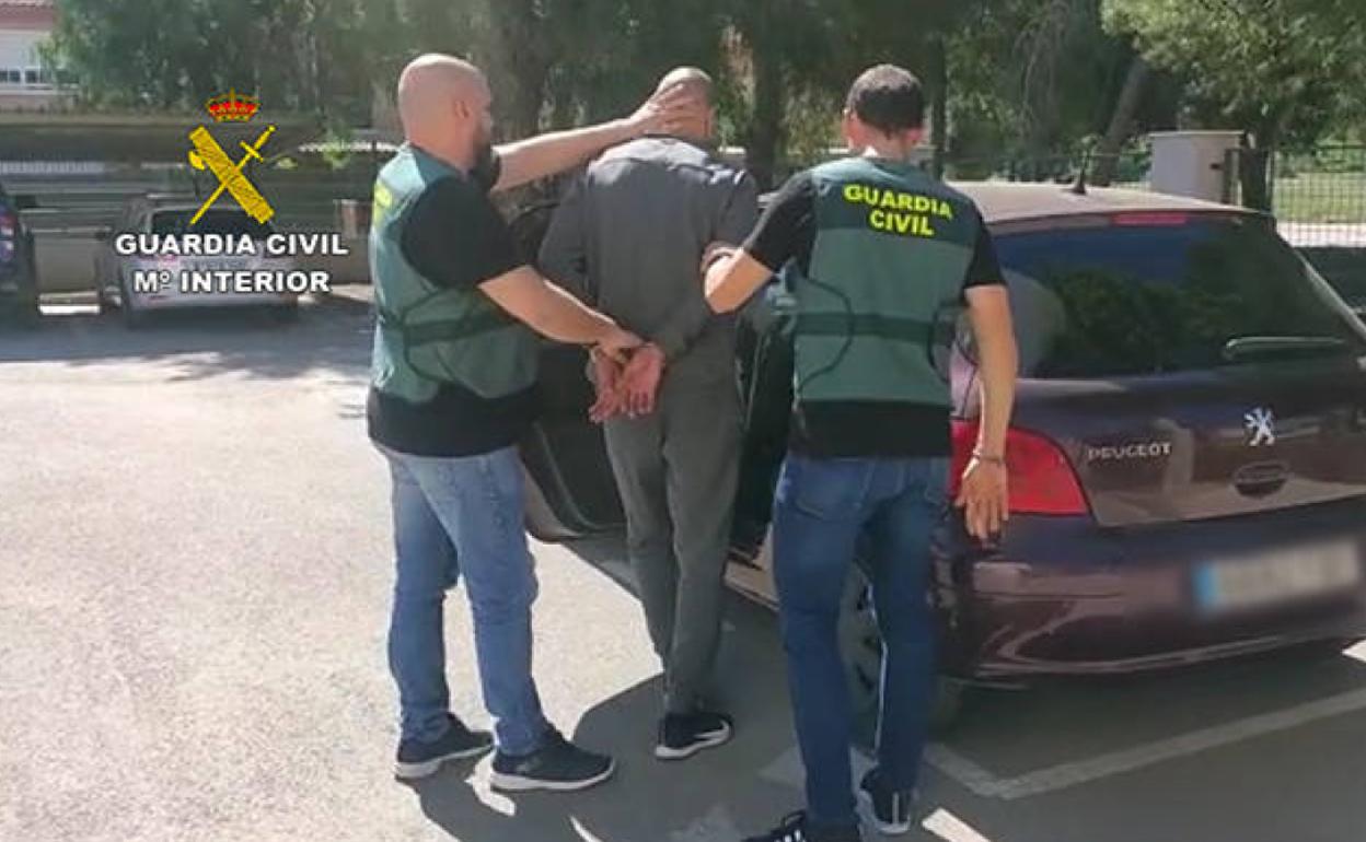 Dos agentes introducen al detenido en un vehículo.