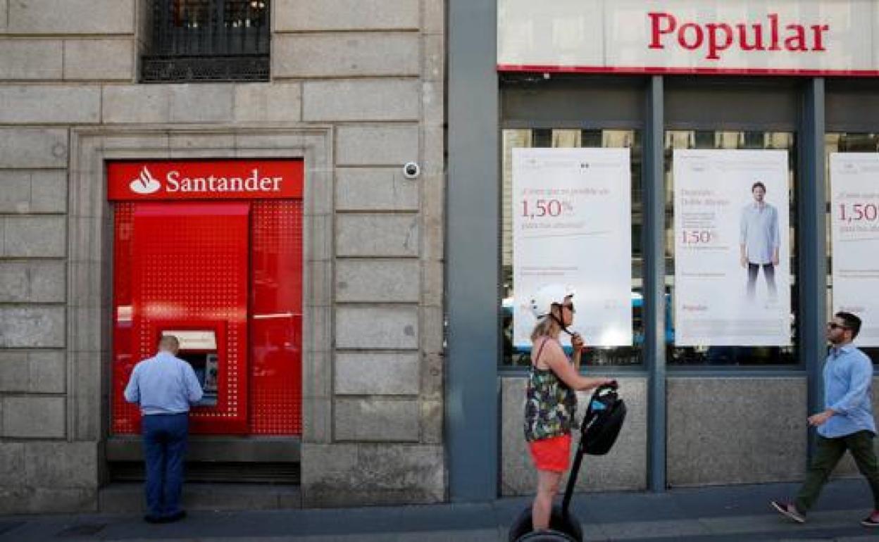 Un hombre saca dinero de un cajero del Santander, en una sucursal del Popular, en 2017. 