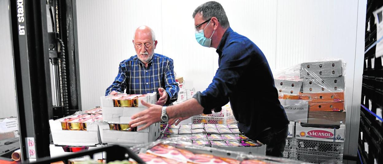 Dos voluntarios del Banco de Alimentos del Segura apilan comida en las instalaciones de Murcia, ayer. 