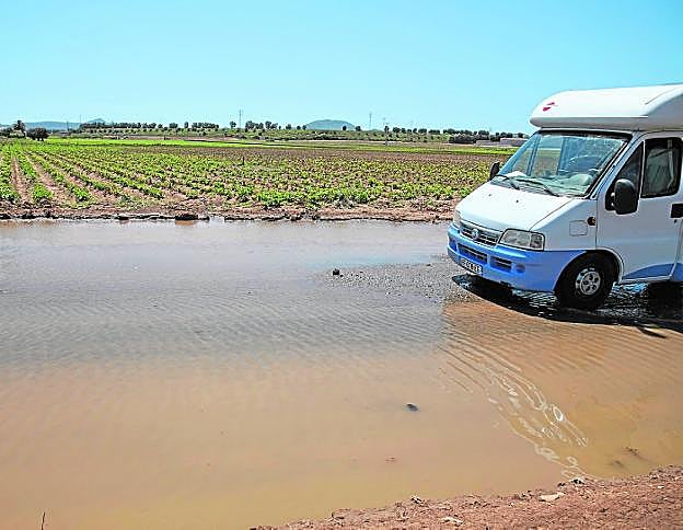 Un vehículo, cruzando ayer un vial de la zona de Los Camachos afectado por el derrame de agua. 