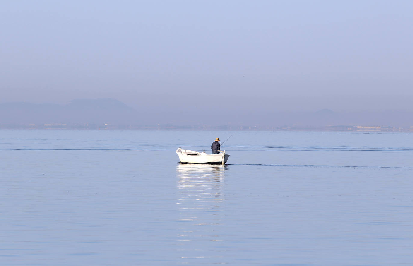 Un hombre pesca en su barca en la zona norte de La Manga. 