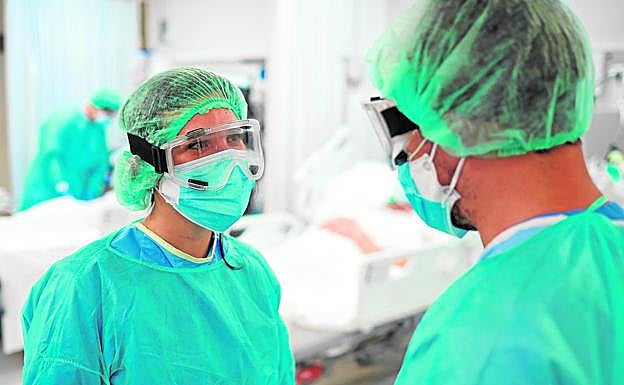 Dos enfermeros, equipados con EPI, conversan en la sala de un hospital. 