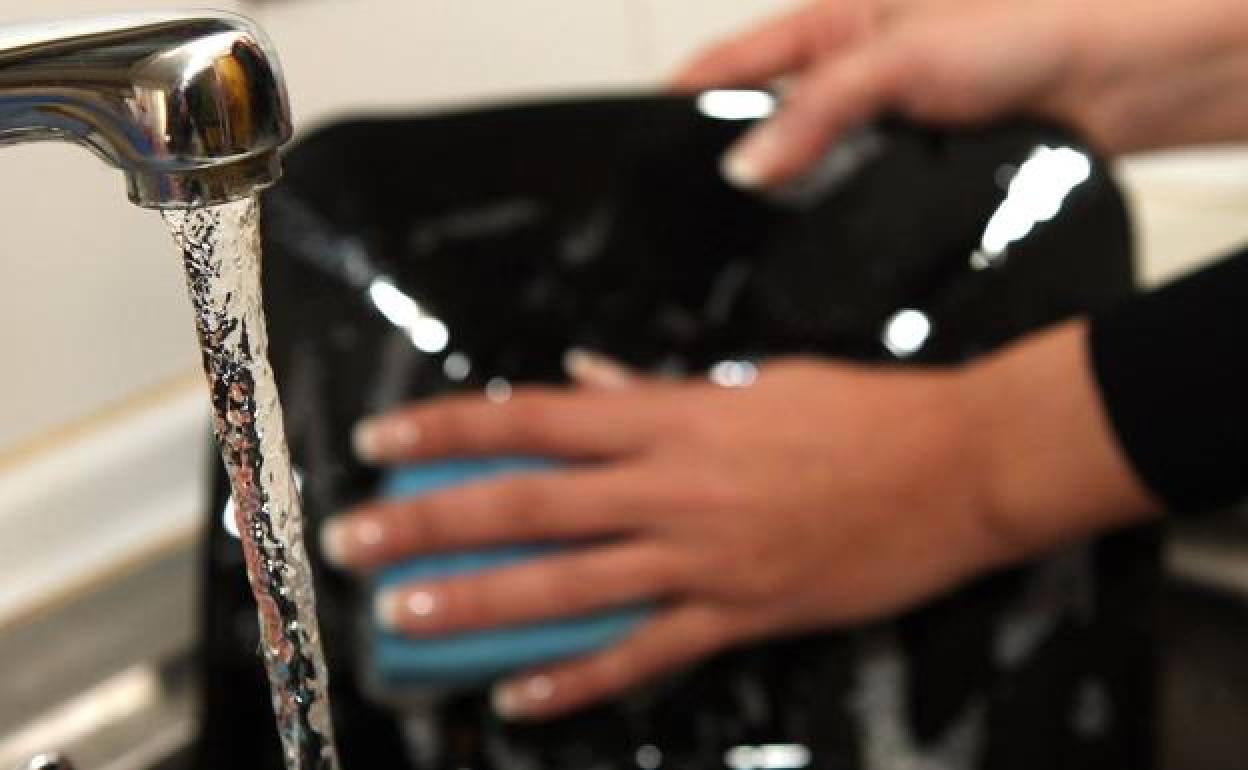 Una persona friega los platos. 