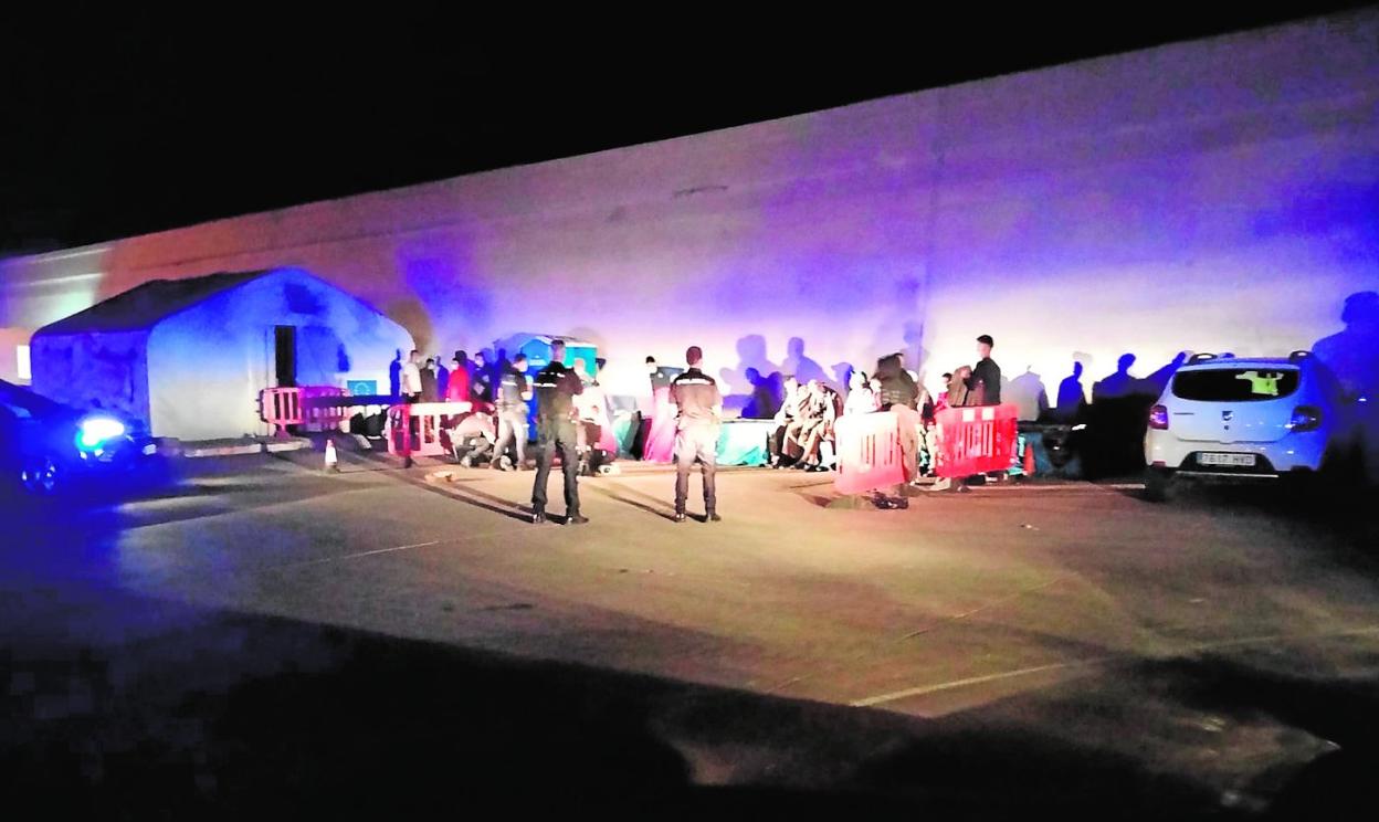 Policías alumbran con los faros de un coche a un grupo de inmigrantes, esta semana en Escombreras, tras fallar el alumbrado público. 