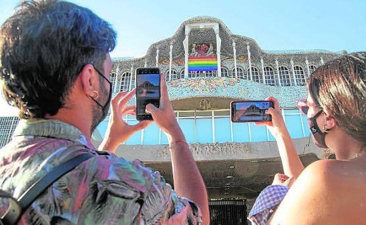 Dos vecinos fotografían la bandera arcoíris en la fachada de la Asamblea Regional, imagen de archivo. 
