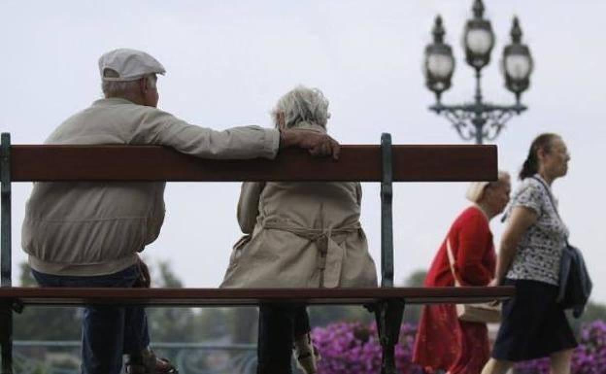 Una pareja de jubilados sentados en un banco.