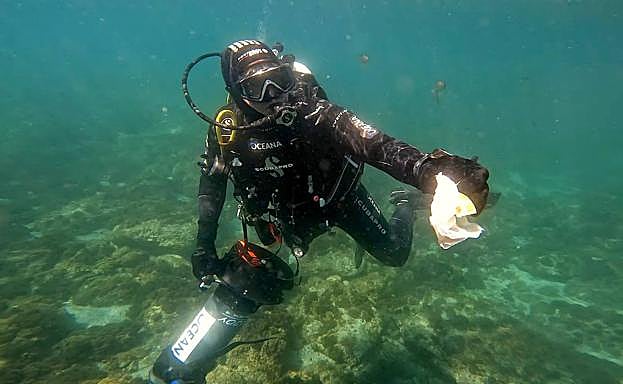 Un buceador de Oceana muestra un residuo de plástico.