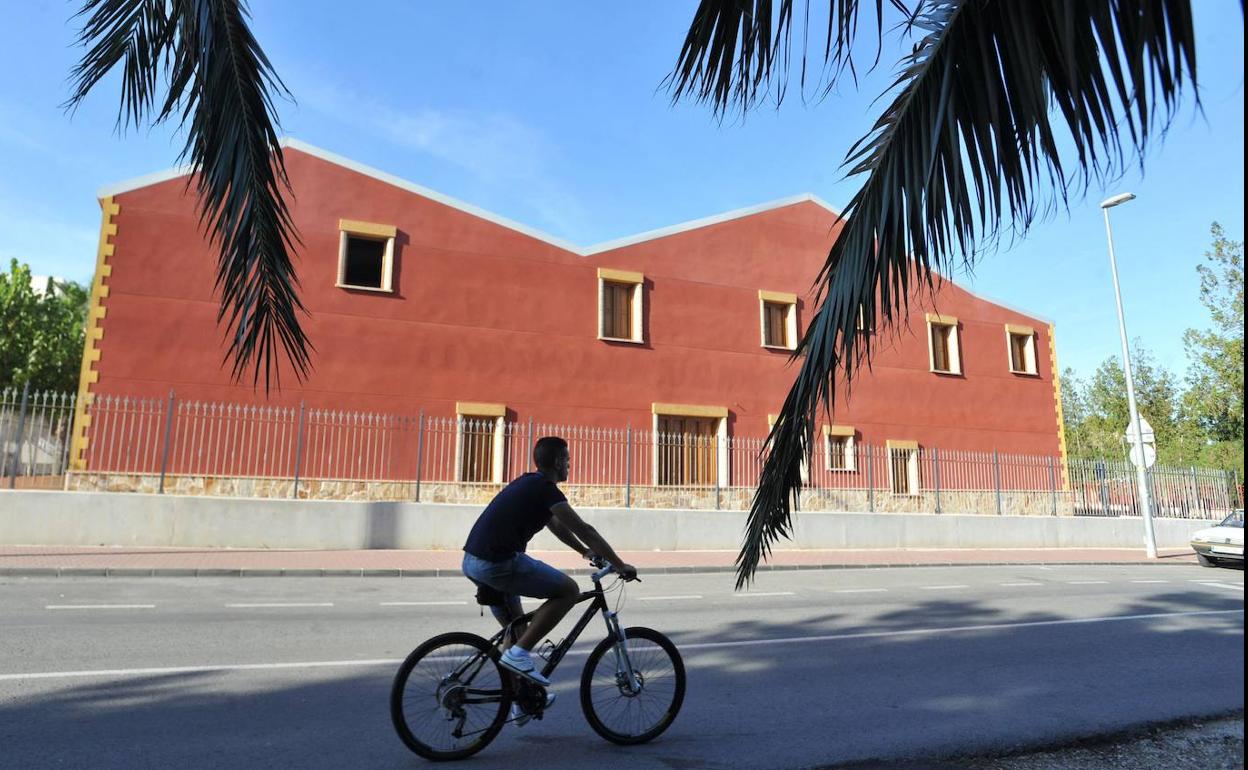 Un ciclista pasa ante el edificio de la sede de La Contraparada en Javalí Nuevo, en una foto de archivo.