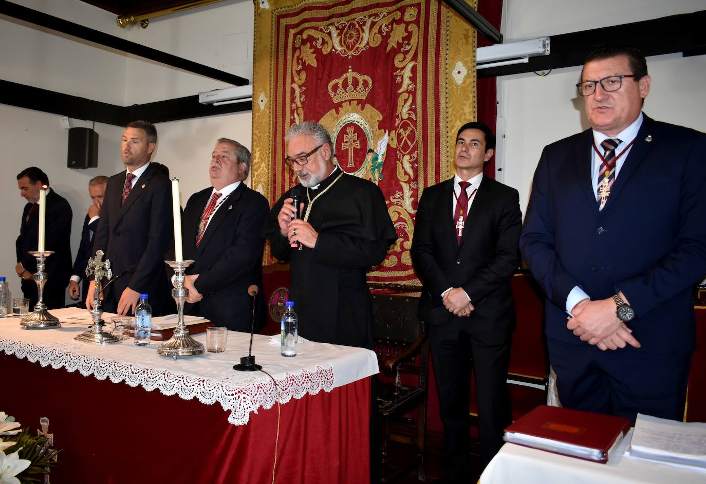 El rector de la basílica, Emilio Sánchez (3º izda), rezando las preces junto al hermano mayor de la Cofradía de la Vera Cruz, Luis Melgarejo, y los componentes de la Junta Representativa durante el cabildo. 