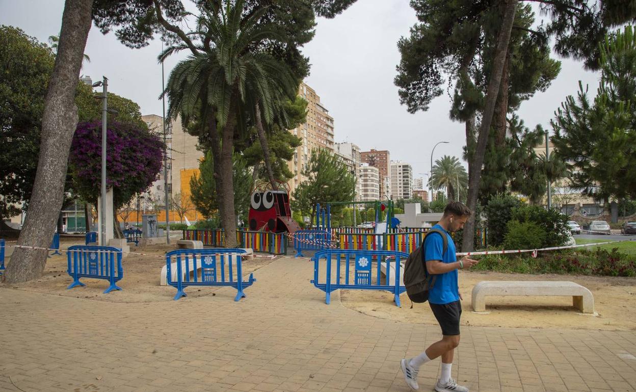 Un hombre pasa delante de unas vallas que acotaban los árboles de la Plaza de España. 