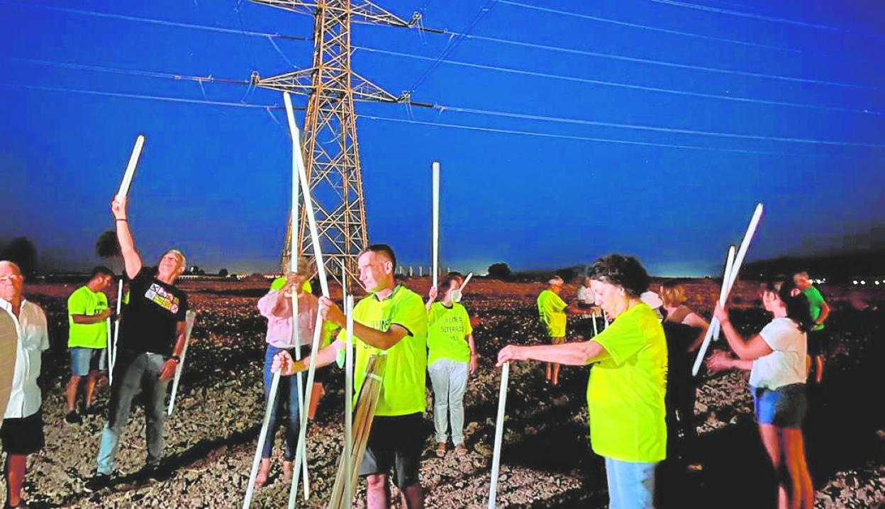 Vecinos de Totana comprueban cómo se iluminan los tubos fluorescentes bajo una línea de alta tensión. 