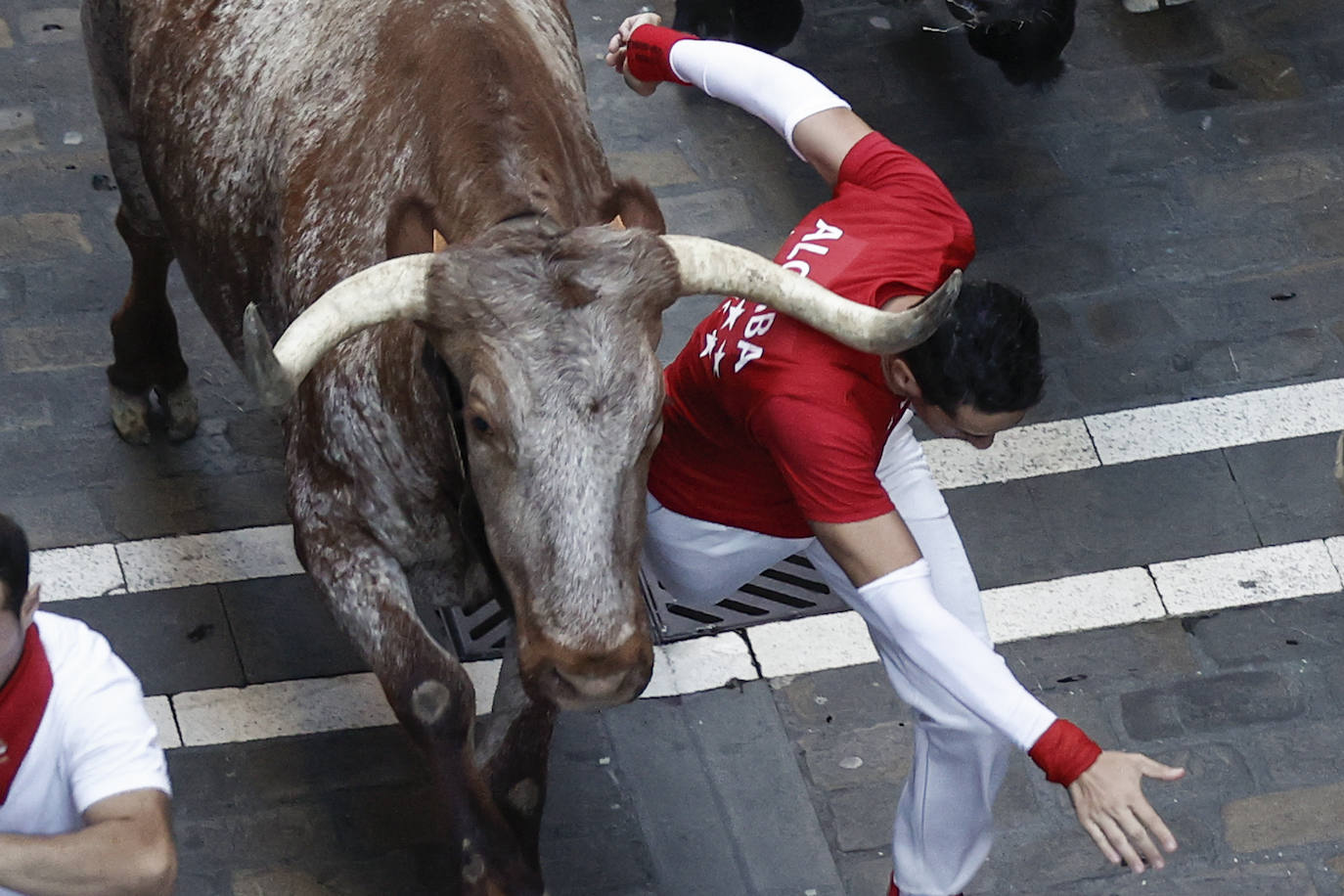 Un mozo pasa rozando a un astado durante el séptimo encierro de los Sanfermines.