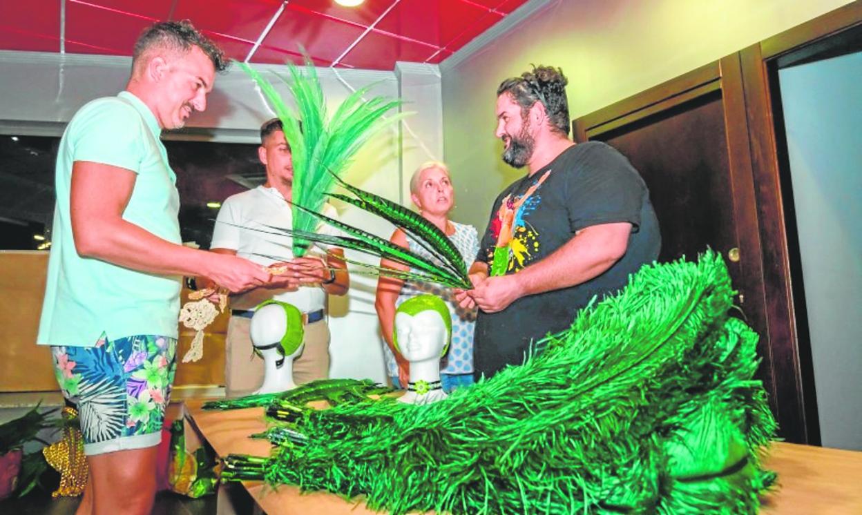 Cuatro miembros de una peña dan los últimos retoques a unos tocados de plumas, el pasado viernes. 