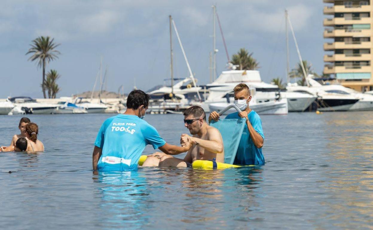 Voluntarios ayudan a un hombre con movidad reducida a darse un baño en una imagen de archivo. 