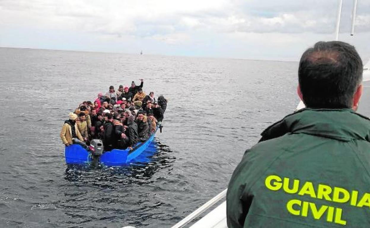 Los ocupantes de una patera, repleta de inmigrantes, esperan el auxilio de la Guardia Civil. 