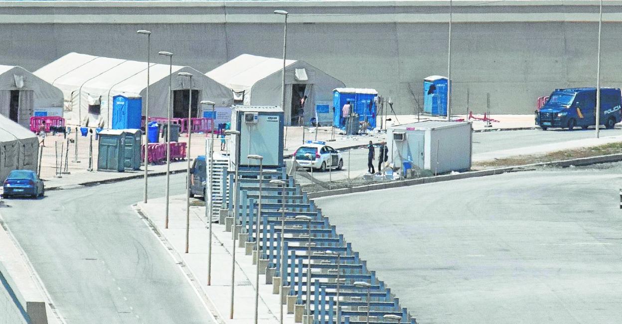 Un vehículo de la Guardia Civil circula junto al control de la Policía, en el campamento temporal de inmigrantes de Escombreras, ayer. 