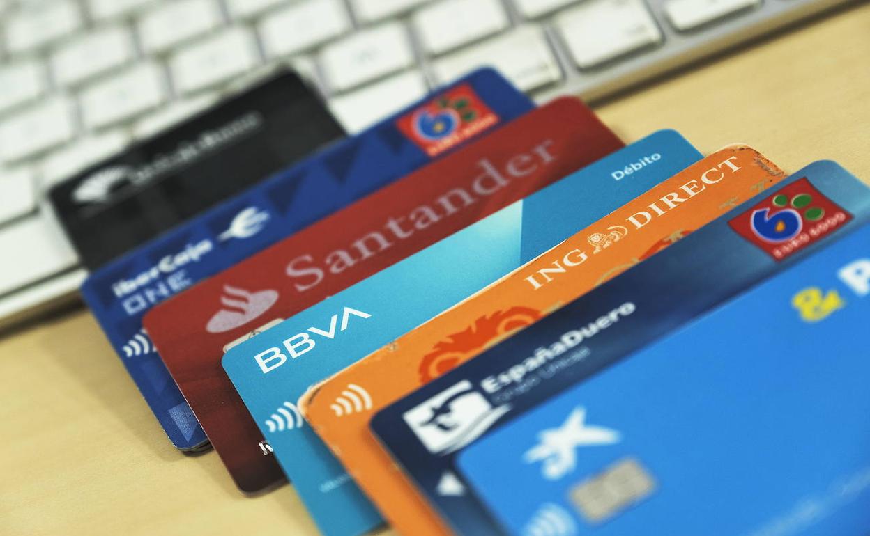 Varias tarjetas de crédito y débito apoyadas sobre un escritorio.