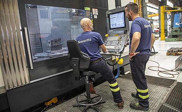 Dos obreros manejan una máquina de alta definición que construye y perfila piezas de motores, en una nave de Navantia.