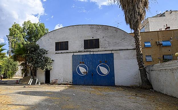 Fachada de la 'nave del aceite', con varios muebles y colchones arramblados en un lateral.