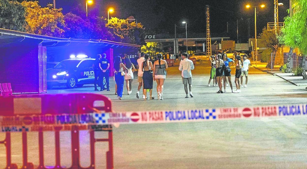 Jóvenes, el miércoles en Cabo de Palos caminando por la zona acotada por la Policía Local con vallas y precintos. 