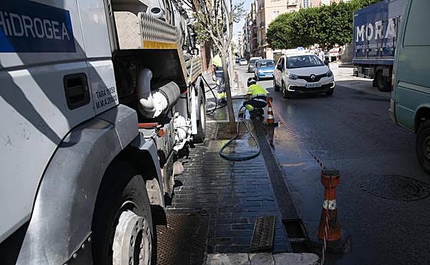 Dos operarios de Hidrogea limpian un imbornal en la calle Caridad, cerca de la Plaza de Risueño.