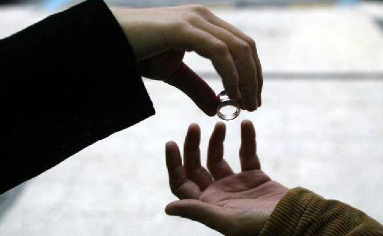 Un anillo de boda entre las manos de una pareja.