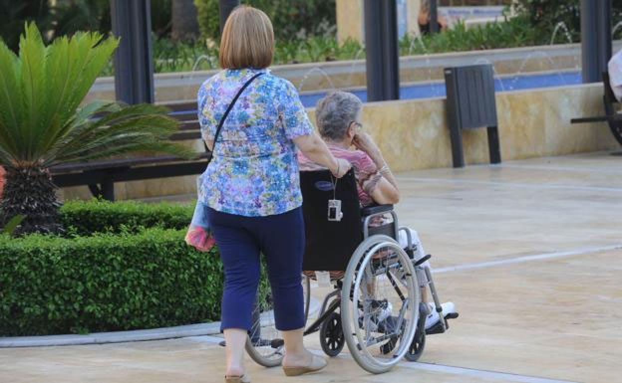 Una mujer empuja la silla de una persona dependiente en una imagen de archivo. 