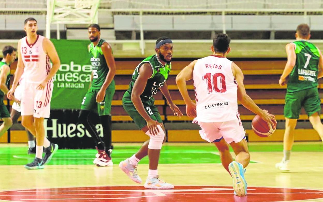 El alero Joaquín Reyes busca el pase a un compañero, anoche en Huesca, vigilado por Adom. 