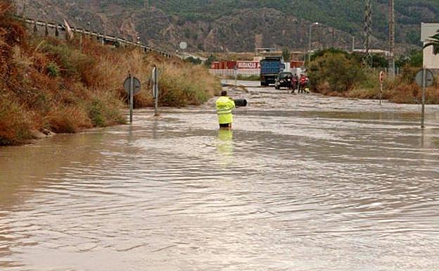 Una persona en una vía de Lorca inundada por la lluvia.