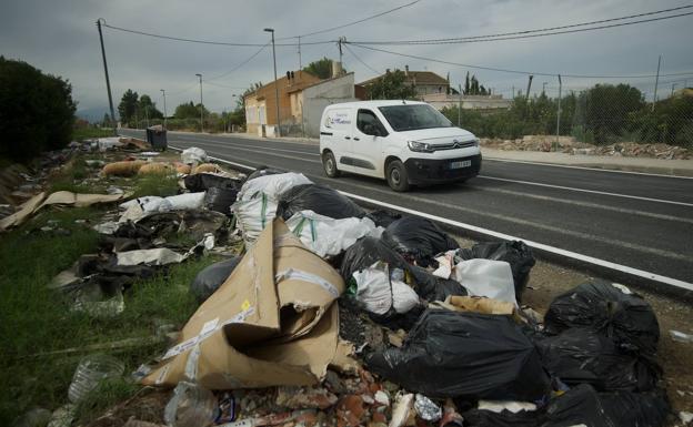 Escombros, cartones, bolsas de basura y otros residuos en el camino del Reguerón, en Alquerías. 