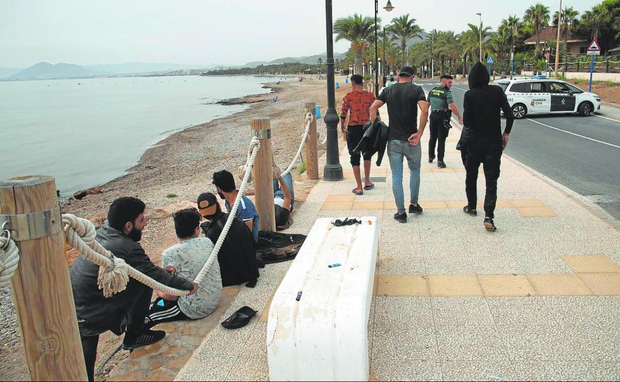 Los inmigrantes, en el paseo marítimo de La Azohía, custodiados por la Guardia Civil y la Policía Local.