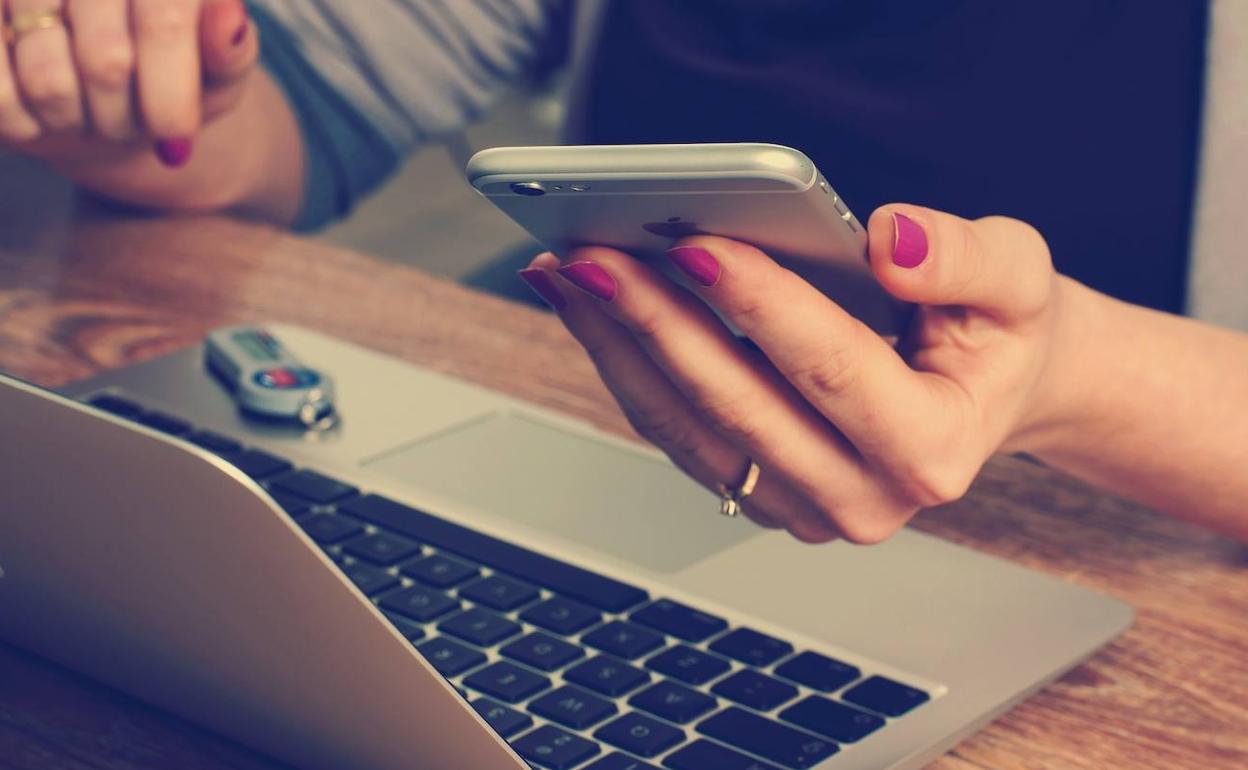 Una mujer sostiene en móvil.