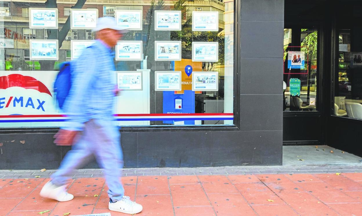Un viandante pasa ante los anuncios de casas a la venta de una inmobiliaria en Murcia. 