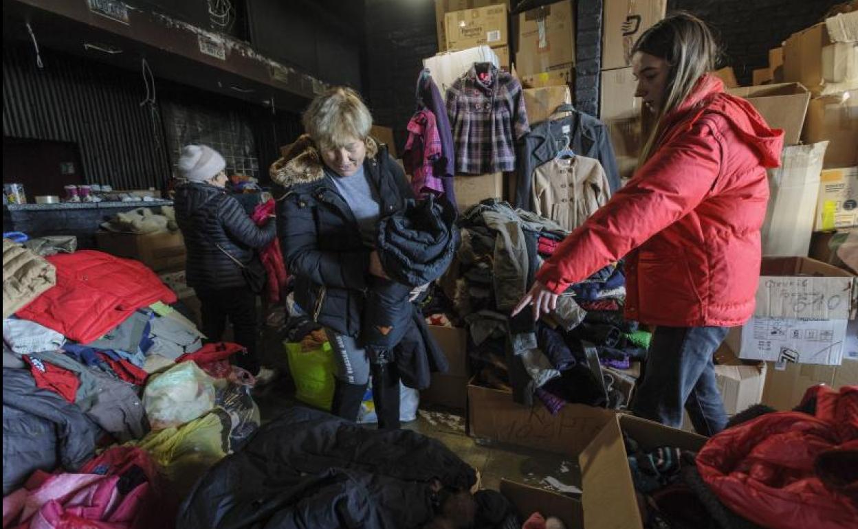 Dos voluntarias clasifican prendas de vestir en una tienda benéfica en la ciudad de Leópolis, al oeste de Ucrania. 