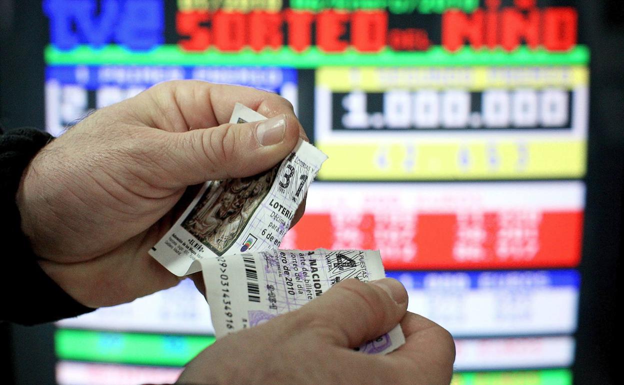Un hombre rompe un décimo del sorteo de Lotería del Niño tras comprobar que su número no ha resultado agraciado. 
