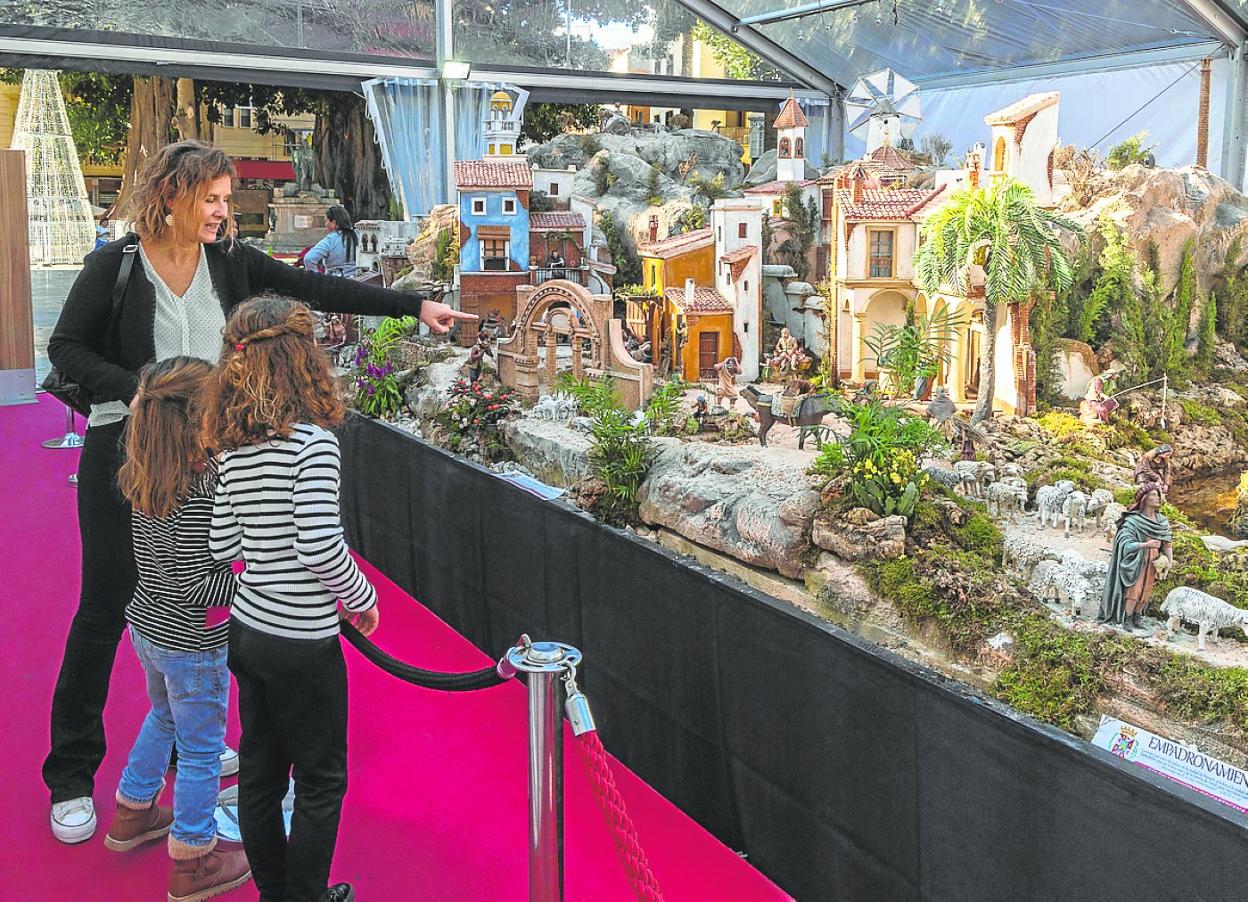 Una mujer explica a dos niñas las figuras del belén municipal de la Plaza San Francisco. 