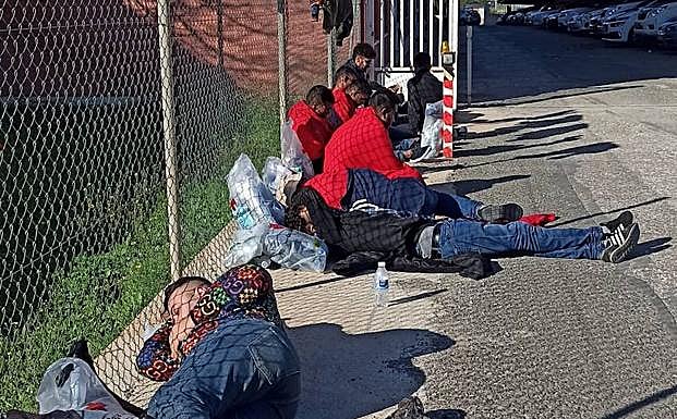 Varios inmigrantes esperan en la calle tras ser interceptados al bajar de la patera en la que viajaban. 