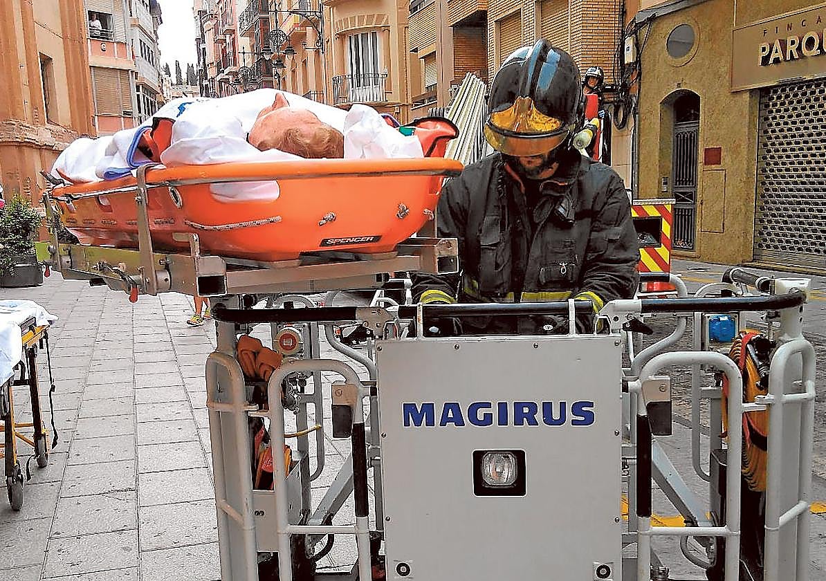 Un bombero evacúa a una persona mayor en la calle del Aire.