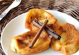 Unas torrijas servidas con dos ramas de canela.