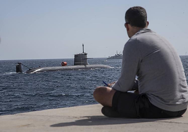 Un joven ve pasar el 'Isaac Peral' desde el faro de Navidad. Al fondo, la popa del 'Neptuno'.
