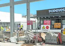 Un grupo de obreros trabaja en el centro comercial de San Antón, donde la firma de restaurantes Popeyes ya ha puesto el cartel para abrir en unas semanas.